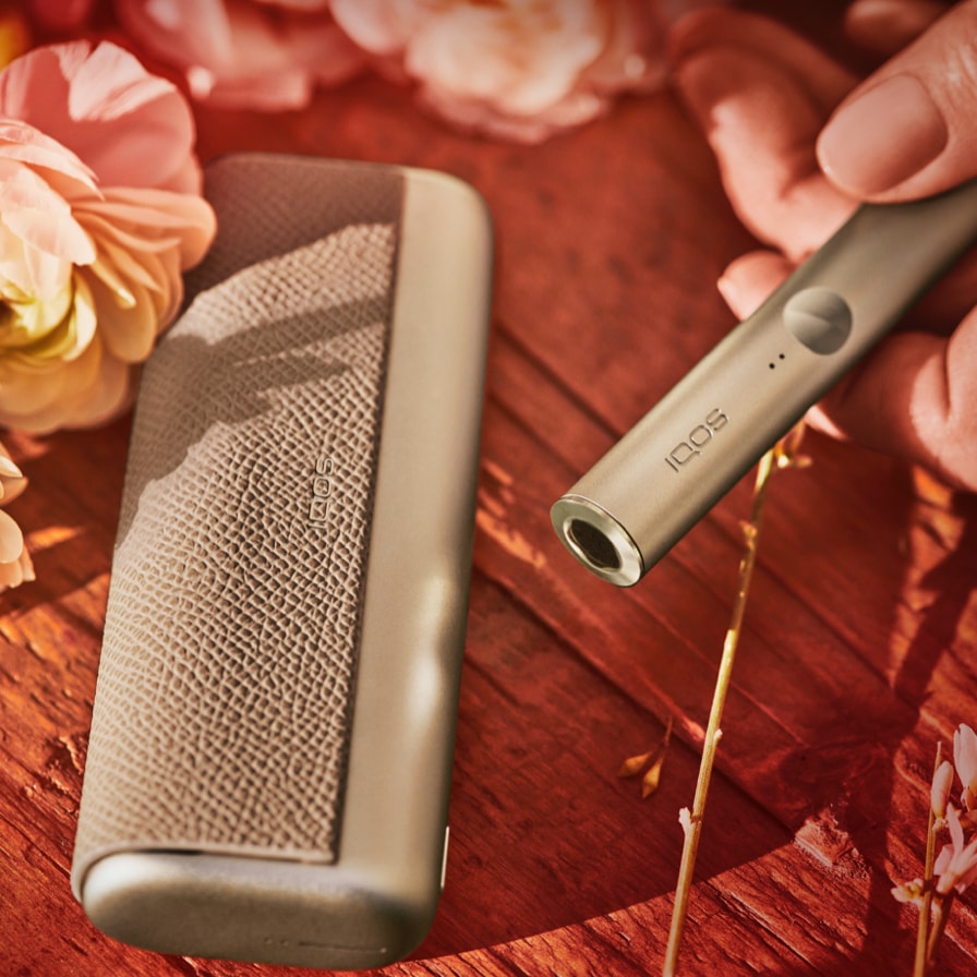 A woman with curly hair holding an IQOS device.