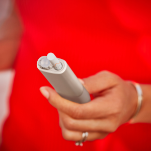 A woman wearing red holds an IQOS ILUMA ONE.