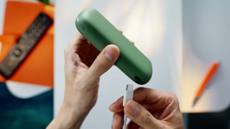 A charging cable being inserted into an IQOS ILUMA holder.