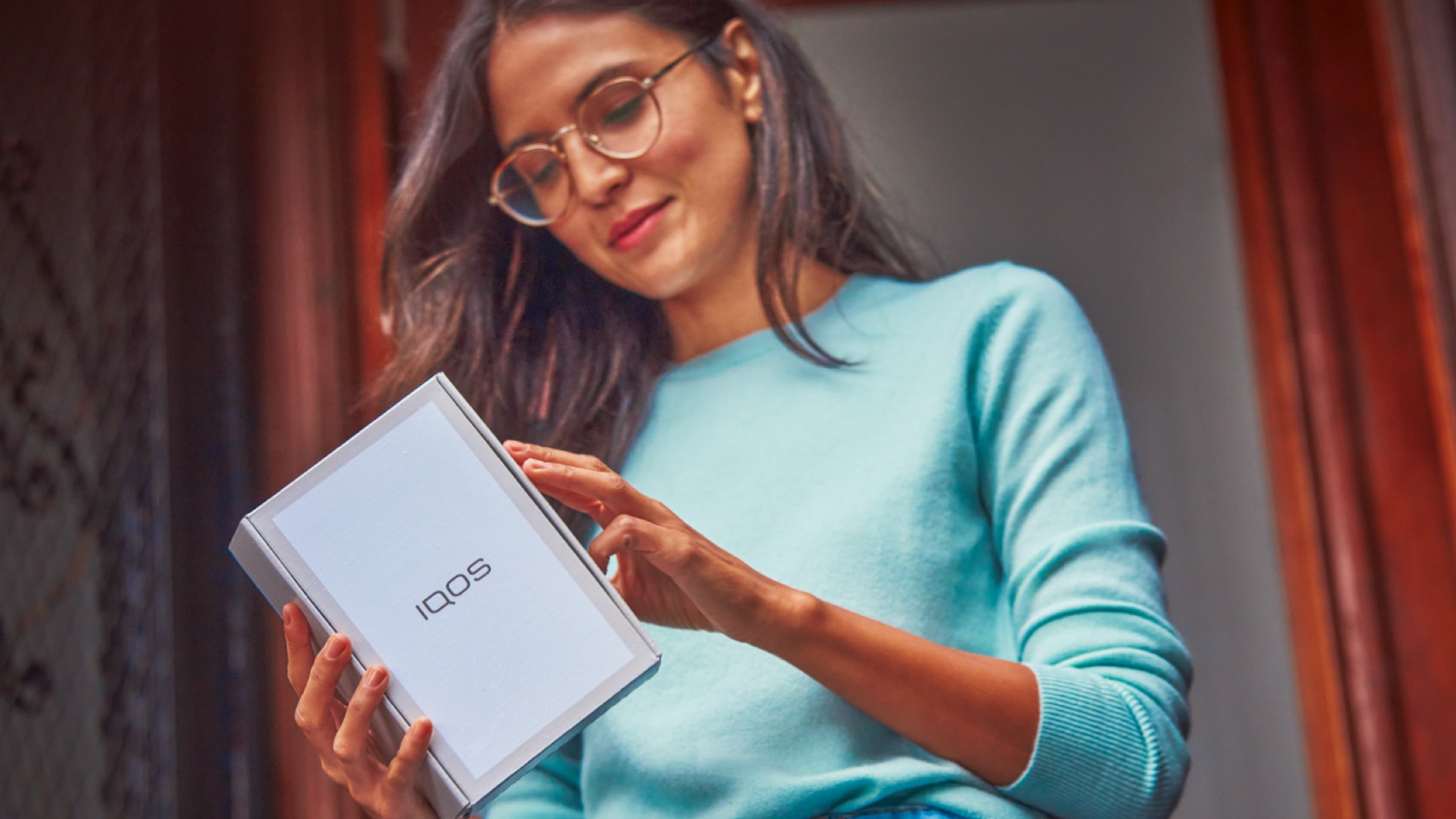 A woman opening a package from IQOS.