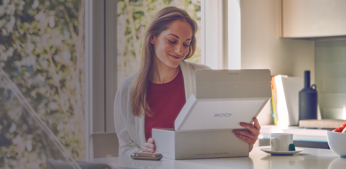 A woman opening an IQOS product box.