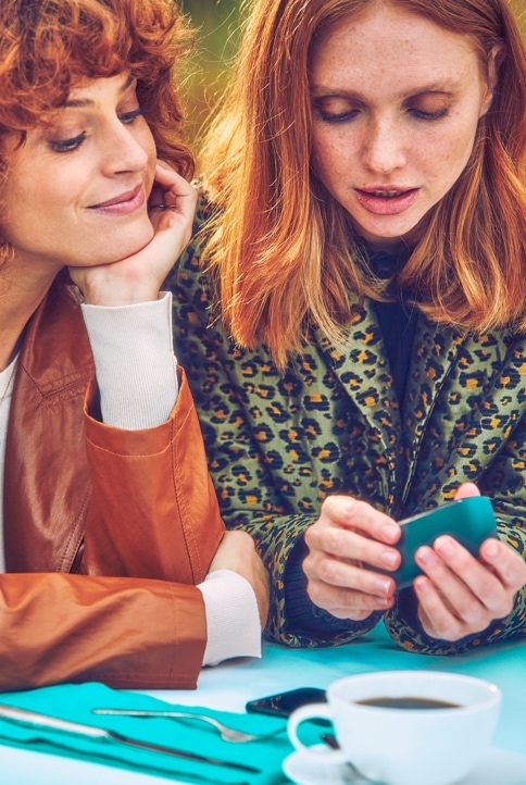 Two women looking at an IQOS device.