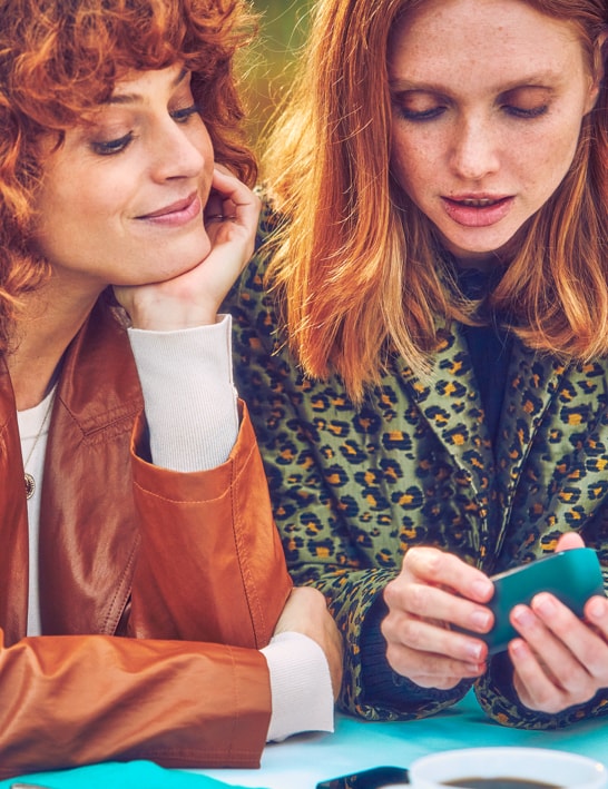 Two women looking at an IQOS device.