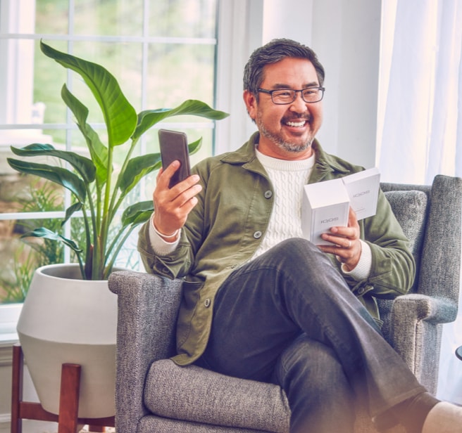 A smiling man holdiing an IQOS device.