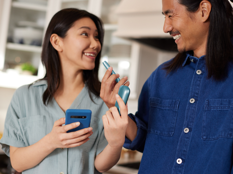 Turquoise IQOS Originals heated tobacco device, held by smiling couple