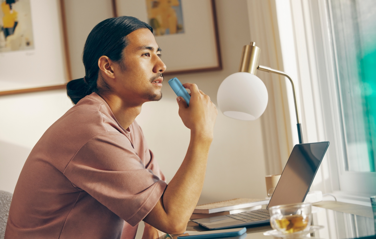 Man holding turquoise IQOS Originals ONE heated tobacco device.  