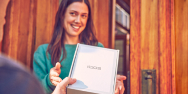 Girl smiling with an IQOS box in her hands
