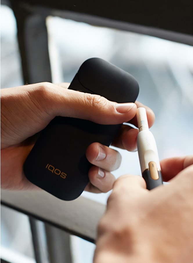 Man with a gold IQOS Duo and a mobile in his hands